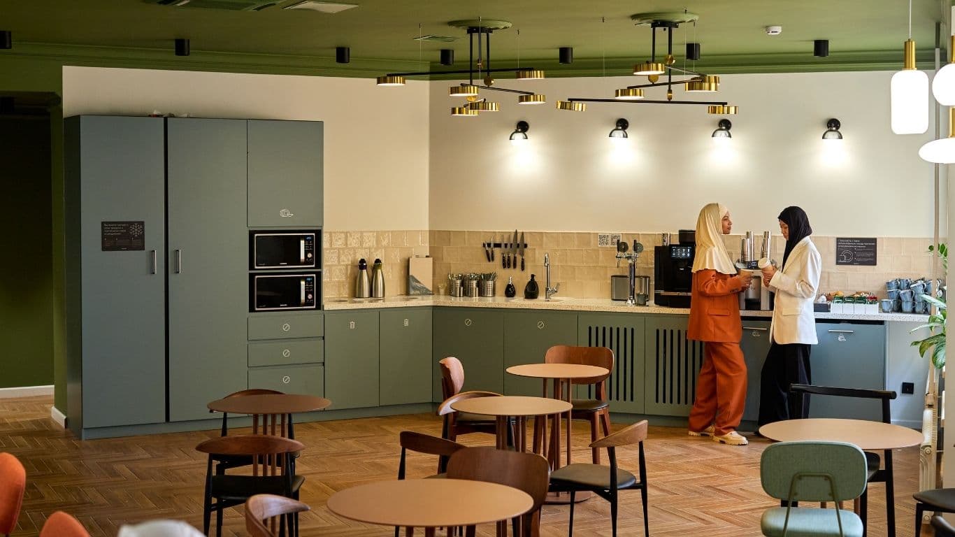Two professionals having a warm conversation in a modern break room